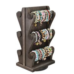 a wooden rack with bracelets and earrings hanging from it's sides on a white background