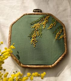 a close up of a embroidery on a piece of cloth with yellow flowers in the background