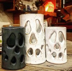 three white and black vases sitting on top of a wooden table