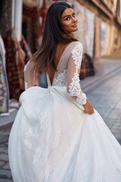 a woman in a white dress is walking down the street with her back to the camera