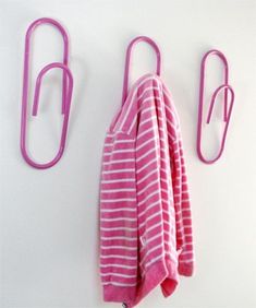 two pink towel hooks are hanging on a white wall next to a pair of scissors