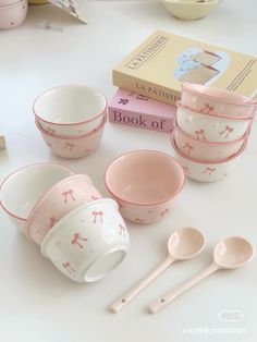 pink and white bowls, spoons, books and other items on a table top