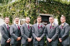 a group of men standing next to each other wearing suits and ties with their hands in their pockets