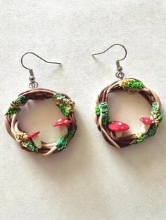 the earrings are made out of wire and have red mushrooms on them with green leaves