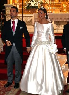 the bride and groom are walking down the aisle together in their wedding gowns,