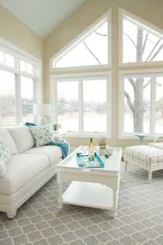 a living room filled with furniture and large windows