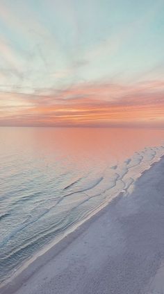 the beach is covered in white sand as the sun sets