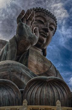 there is a large buddha statue in front of a cloudy blue sky with the words