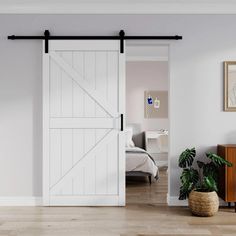 an open sliding door in a bedroom with white walls and wood floors, along with a plant