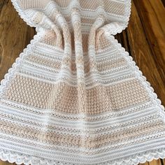 a white crocheted blanket sitting on top of a wooden floor