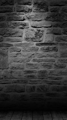 a black and white photo of a brick wall with wood flooring in the foreground