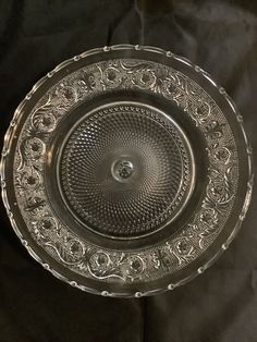 an ornate glass plate on a black tableclothed surface, with a circular design in the center