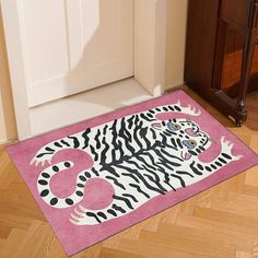 a pink rug with a white tiger on it in front of a wooden cabinet and door