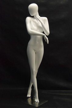 a white female mannequin is standing on a black surface with its arms crossed