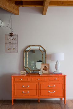 an orange dresser with a mirror on top of it