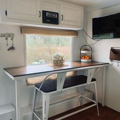 a kitchen area with a table, counter and television mounted on the wall above it