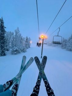 two skiers are standing in the snow under a ski lift