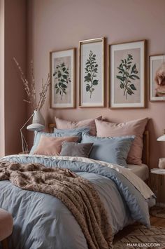 a bedroom with pink walls and blue comforter on the bed, two framed pictures above it