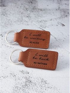 two leather keychains with writing on them