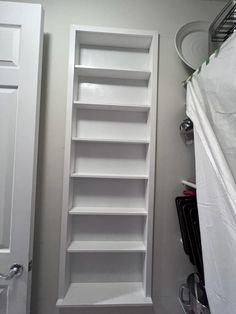 an empty white book shelf in the corner of a room next to a closet door