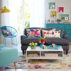 a living room filled with lots of furniture and colorful pillows on top of it's couches