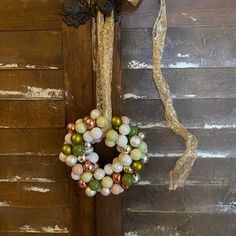 a wreath hanging on the side of a wooden door next to a string and ribbon