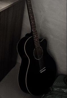 a black acoustic guitar leaning against a wall