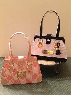 two purses sitting on top of a table next to each other, one pink and one black