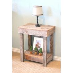 a small wooden table with two potted plants on it and a lamp next to it