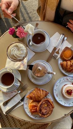 a table topped with different types of pastries and cups of coffee next to each other