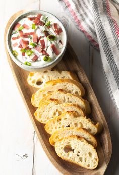 slices of bread on a wooden platter with a bowl of dip