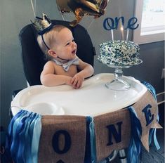 a baby sitting at a table with a cake