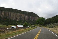 an empty road in front of a mountain