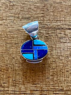 This beautifully well crafted Oval Pendant has been handmade by a Navajo Artisan. The Colors of the Pendant come from Lapis Lazuli, Turquoise and Blue Opal. The Pendant measures 1” long and 1” wide. It is stamped Sterling and signed by the Artist. “Winds of Wisdom” (Lapis Lazuli, Turquoise and Blue Opal. The Navajo (Dine’) believe that the wind is a powerful source. The native tradition believes that at any moment, the blowing wind can inspire one with hope, resolve, and great wisdom. Wisdom has Blue Necklace With Round Inlay, Southwestern Blue Oval Jewelry, Southwestern Style Blue Oval Jewelry, Artisan Blue Inlay Necklaces, Blue Oval Southwestern Jewelry, Oval Blue Southwestern Jewelry, Traditional Blue Oval Beads Jewelry, Traditional Blue Oval Beaded Jewelry, Artisan Blue Jewelry With Inlay