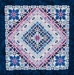 a blue and white quilt with an intricate design on the center, in front of a black background