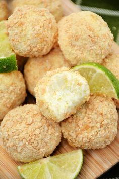 some food that is sitting on a wooden plate with limes and lemon wedges