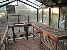 two wooden benches sitting inside of a greenhouse