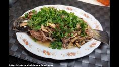 a white plate topped with meat and veggies on top of a black table