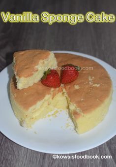 vanilla sponge cake on a white plate with two strawberries cut in half to show the inside