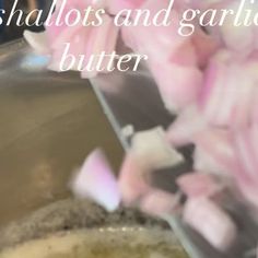 pink flowers are being chopped into chunks in a metal bowl with the words shallots and garlic butter on it