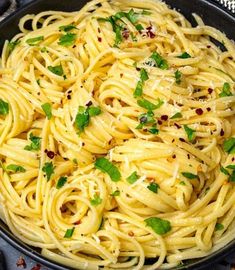 a pan filled with pasta and garnished with parsley on the side,