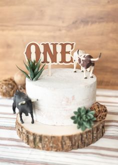 there is a small cake with one on it and an animal figurine next to it