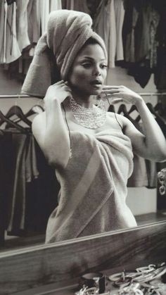 a black and white photo of a woman brushing her hair in front of a mirror