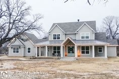 a large gray house sitting in the middle of a dry grass field with lots of trees