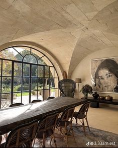 the dining room table is surrounded by large arched windows and an art work on the wall