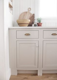 a kitchen with white cupboards and wooden cutting board on top of the cabinet doors