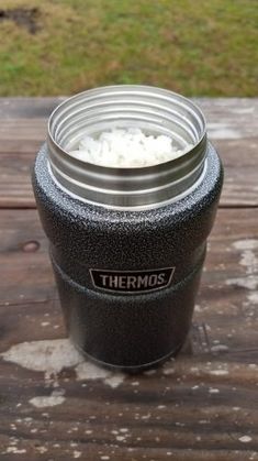 thermos is sitting on a picnic table with rice in it's cup