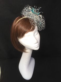 Teal blue and silver veiled fascinator perfect for the guest who wants something beautifully unique. This design is a beautiful selection of glass effect leaves and flowers clustered together amongst a fine layer of veiling and set onto a fine comfort base tiara band. As with all our designs, this piece can be made exact to the image or in any colour combination to match in with your outfit. If a specific colour is required customers can message over an image of their outfit and accessories, or Silver Fascinator, Gold Fascinator, Teal And Silver, Blue Fascinator, Wedding Headdress, Gold Hats, Glass Effect, Wedding Hat, Wedding Fascinators