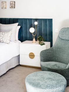 a bed room with a neatly made bed and a night stand next to a chair