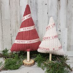 two knitted christmas trees sitting on top of a wooden stand next to each other